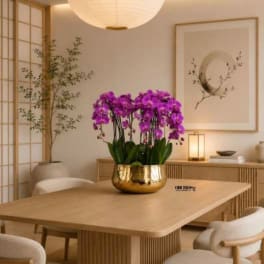 Purple orchids in a gold bowl on a wooden table