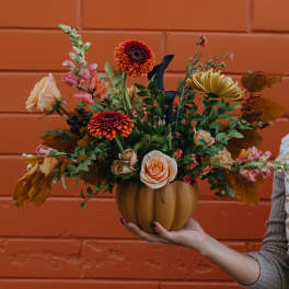 Autumn floral arrangement in a pumpkin-shaped vase with roses and mums
