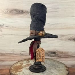 Black witch hat decoration on a stand with a hanging tag