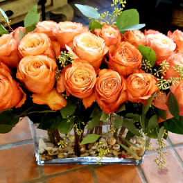 Orange roses arranged in a clear rectangular vase