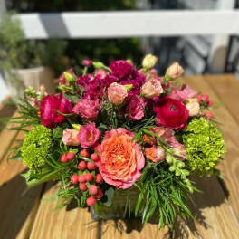 Pink and red mixed flower arrangement in a square container