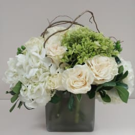 White and cream roses with green hydrangea in a square glass vase
