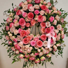 Large pink rose wreath on a black stand with a pink ribbon