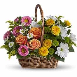 Basket arrangement of roses and daisies in pink, yellow, orange, and white
