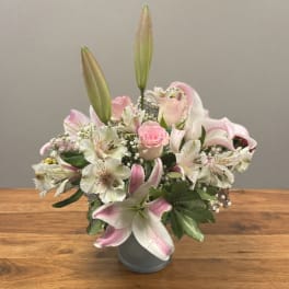 Pink and white lilies with a pink rose in a gray vase