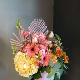 Pink and yellow mixed flower arrangement in a pink vase