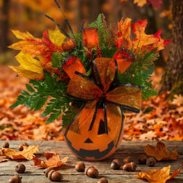 Halloween bouquet in a jack-o'-lantern vase with autumn leaves and ribbon