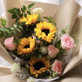 Bouquet of sunflowers and pink roses wrapped in beige paper