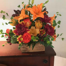 Orange lilies and red chrysanthemums in a wooden box arrangement