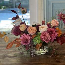 Mixed pink and peach flower arrangement in a clear glass bowl