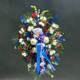 Large standing floral spray with red, white, and blue flowers and ribbon