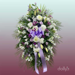 Standing floral spray with white and lavender flowers and a purple ribbon