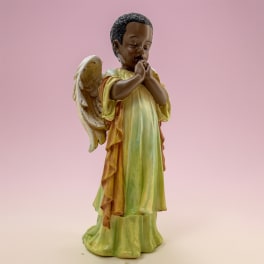 Small angel figurine with folded hands on a pink background
