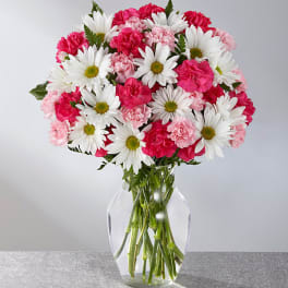 Pink carnations and white daisies in a clear glass vase