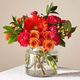 Orange and pink flowers arranged in a clear glass vase