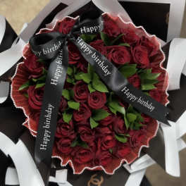 Bouquet of red roses wrapped with black and white paper and birthday ribbons