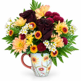 Bouquet of dark roses and mixed daisies in a floral mug vase