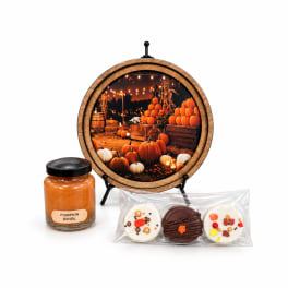 Pumpkin-themed candle jar, decorative sign, and packaged cookies on a white background