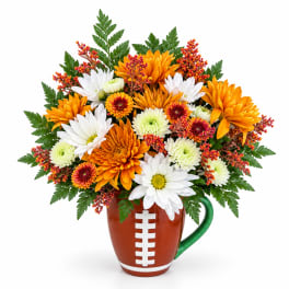 Football-shaped mug holding orange and white daisies and mums