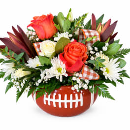 Football-shaped vase with roses and white daisies