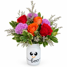 Bouquet of red, orange, and purple flowers in a white jar with a ghost face