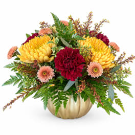Yellow and burgundy flowers arranged in a gold pumpkin vase