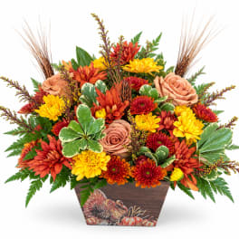 Autumn floral arrangement in a decorative wooden container with orange and yellow blooms