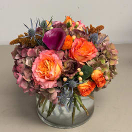 Mixed bouquet of orange and pink roses in a clear glass vase