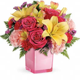 Pink roses and yellow lilies arranged in a pink glass vase