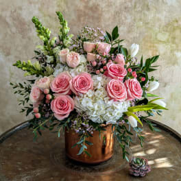 Pink roses and white hydrangeas arranged in a copper vase