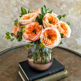 Peach roses arranged in a glass vase on stacked books