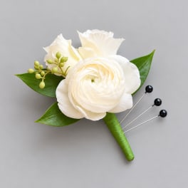 White floral boutonniere with green leaves and berry accents