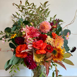 Mixed bouquet of dahlias, roses, and sunflowers in a clear glass vase