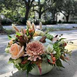 Pumpkin-shaped vase with peach and white flowers and dried grasses