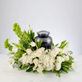 White floral arrangement around a dark blue urn