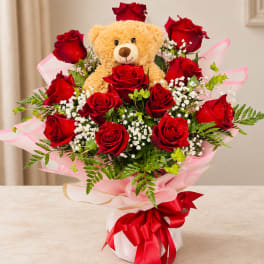 Red rose bouquet with a teddy bear centerpiece and pink wrapping