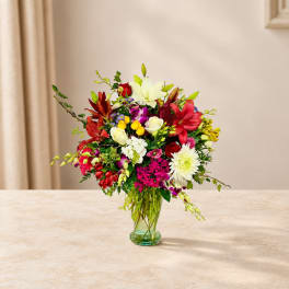 Mixed bouquet of lilies, roses, and orchids in a glass vase
