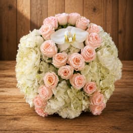 Round bouquet of pale pink roses and white hydrangeas with a white orchid center