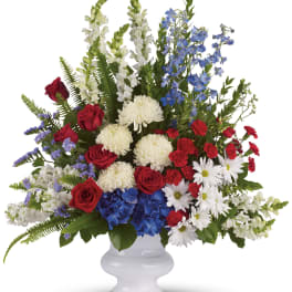 Tall red, white, and blue flower arrangement in a white pedestal vase