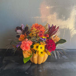 Colorful autumn flower arrangement in a pumpkin-shaped container