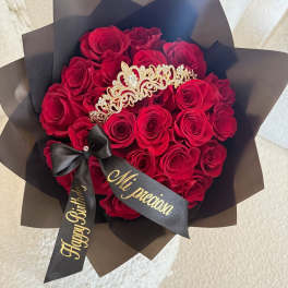 Bouquet of red roses wrapped in black paper with a tiara and ribbon