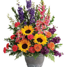 Colorful bouquet with sunflowers, roses, and purple blooms in a gray vase