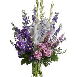 Purple roses and white gladiolus in a clear glass vase