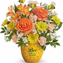 Bouquet of orange and yellow flowers in a bee-themed vase