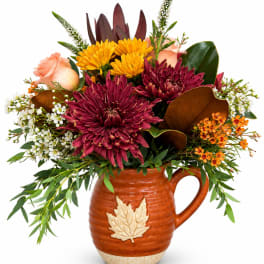 Autumn bouquet in a ceramic pitcher with burgundy, yellow, and peach flowers