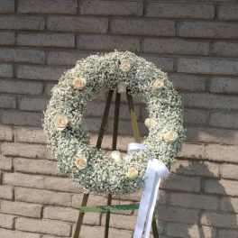 Round floral wreath of white baby's breath with cream roses on an easel