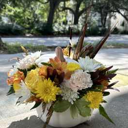 Autumn floral arrangement in a white pumpkin vase with yellow, white, and peach blooms