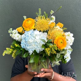 Bright mixed bouquet in a clear glass vase with blue hydrangea and orange blooms