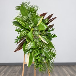 Tall tropical plant arrangement on a wooden easel with layered green foliage
