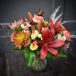 Mixed bouquet with red lilies, chrysanthemums, and roses in a glass vase